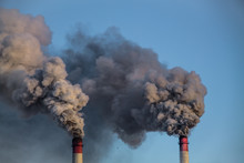 Industrial Chimneys With Heavy Smoke Causing Pollution On The Blue Sky Background