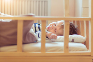 Closeup portrait of sleeping 2 years old baby boy covered with white blanket