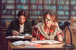 © proimagecontent - Portrait of two successful students casual stylish, boy and girl in library reading hall, evening time, education concept