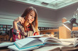 © proimagecontent - Successful casual stylish student girl wears glasses studying hard with books in the library, education concept