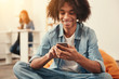© Viacheslav Yakobchuk - Cosy. Relaxed cheerful smiling student sitting in a comfortable orange beanbag chair and browsing the Internet in his smartphone