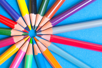 Wall Mural - Wooden color pencils on a blue background. The tips of the pencils look in the center of the circle. The wooden texture of the pencils.