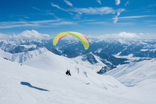 Paraglider Flying Between The Jagged Snowy Peaks