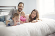 © Louis-Photo - four peoples family on a white bed.