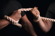 © fortton - Tug-of-war. Men tighten a rope on a black background