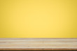 © ijeab - Empty wooden deck table over yellow wallpaper background.