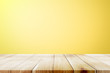 Empty wooden deck table over yellow wallpaper background.