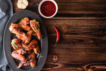 Chicken legs and chicken wings in a sauce fried on a wooden background. Top view. Copy space. 