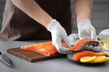 Wall Mural - Man with fresh salmon fillet in kitchen