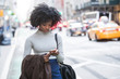 © Haydiddle - Woman using smartphone while walking outdoors