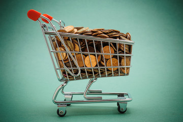 Wall Mural - Shopping trolley with coins on a green background