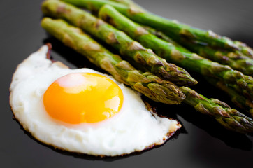 Wall Mural - Fried egg and roasted fresh asparagus in black plate