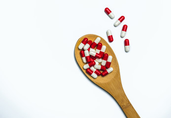 Wall Mural - Colorful of antibiotics capsule pills in wooden spoon are spilling on white background with copy space. Antibiotic drug use with reasonable and health insurance concept.