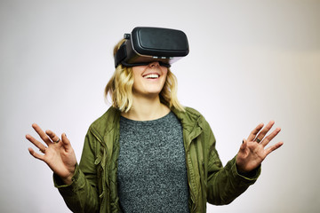 young woman wearing virtual reality goggles white background