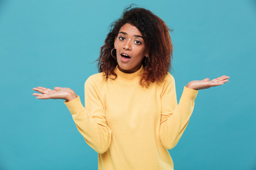 Wall Mural - Confused young african lady dressed in warm sweater