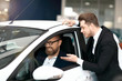 Salesman in suit showing new car to customer