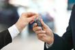 Close-up image of the car salesman hand giving a key to new owner