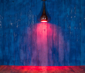 Wall Mural - red light spotlight on a blue wooden wall