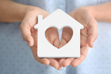 Sticker - Woman holding wooden figure of house, close up