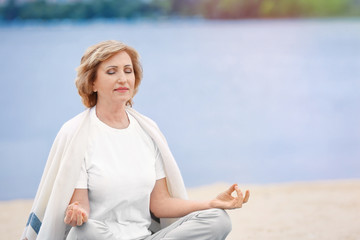 Wall Mural - Elderly woman doing yoga on beach