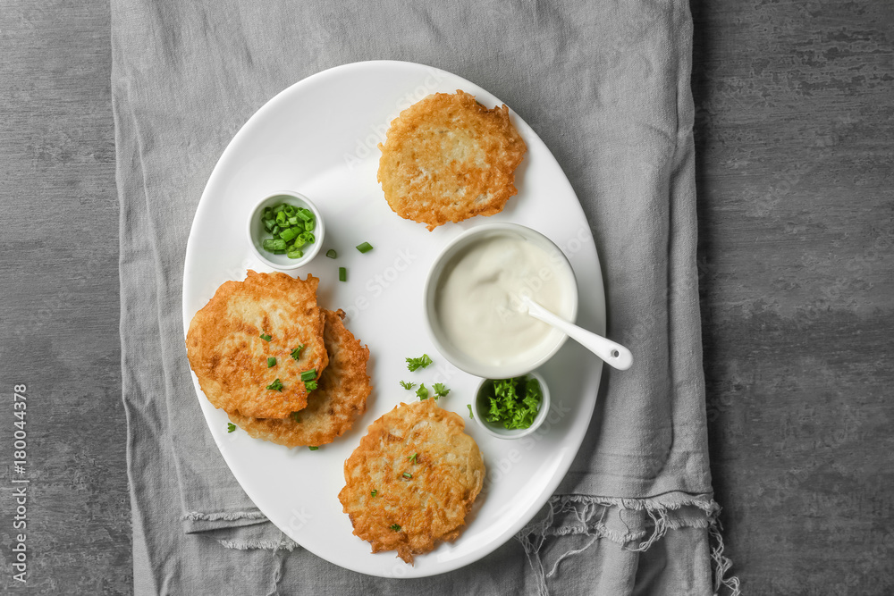 Plate with Hanukkah potato pancakes and sauce on table