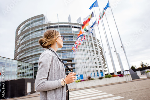 Fotografía Young woman tourist standing with photo camera in front of the European parliame