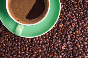 Green coffe cup on coffee beans