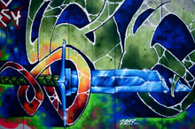 A Fragment Of Detailed Graffiti Of A Drawing Made With Aerosol Paints On A Wall Of Concrete Tiles. Background Image Of Street Art With A Fairy-tale Crystal Sword