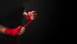 © happy_author - Woman is wrapping hands with red boxing wraps on black background with copy space. Strong hand and ready for fight, active exercise and sparring.  Women self defense.