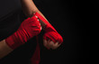 © happy_author - Female boxer is wrapping hands with red wrap, black background with copy space. Strong, ready for fighting or sparring. Women self defense.
