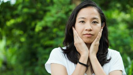 Wall Mural - Asian woman long hair with facial epression green nature background