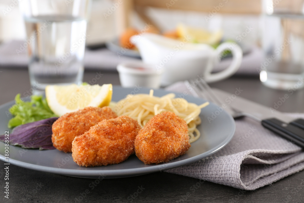 Plate with tasty salmon croquettes and spaghetti on table
