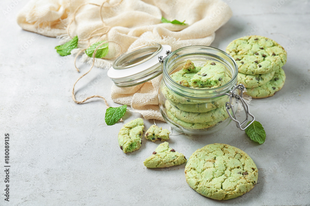 Jar with mint chocolate chip cookies on table