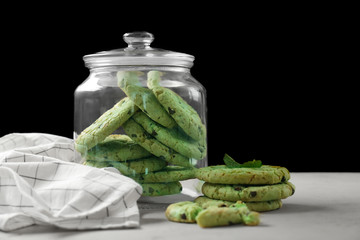 Wall Mural - Jar with mint chocolate chip cookies on table against black background