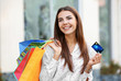 © Africa Studio - Young woman with shopping bags and credit card outdoors