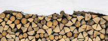 Firewood Logs Covered With Snow. Winter Texture Pattern Background.