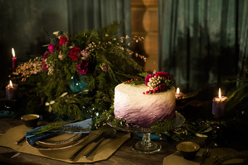 Beautiful purple cake with streaks of white cream and decorated with berries BlackBerry, blueberry and cherry. Over blue wooden table. Dark rustic style.