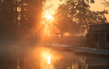 Wall Mural - boats in a lake during an foggy, autumn sunrise in a park. lyon, france.