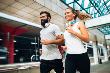 Wall Mural - Young fitness couple running in urban area