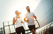 © NDABCREATIVITY - Young fitness couple running in urban area
