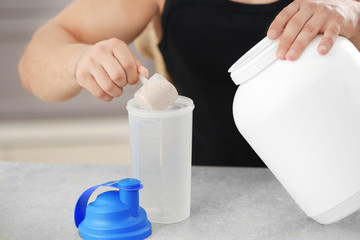 Wall Mural - Young sporty man preparing protein shake at table