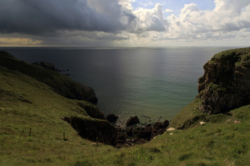 Wall Mural - Moody Pembroke coastline with dak clouds sea cliffs and rocky headland