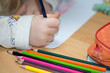 Kind malt und bastelt mit Buntstiften und Schere in Schule,Kindergarten und Hort