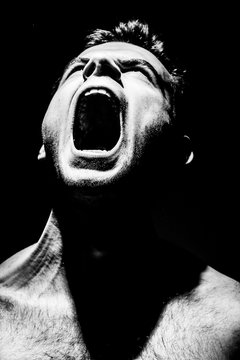 Fototapete - angry man screams on a black background, aggression