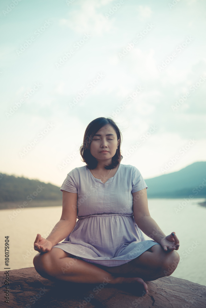 Pregnant woman sit on the rock for play yoga side dam,vintage style,pastel tone,dark,film