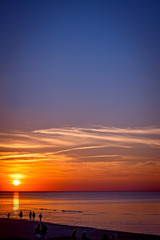 People walking on the sea beach at sunset