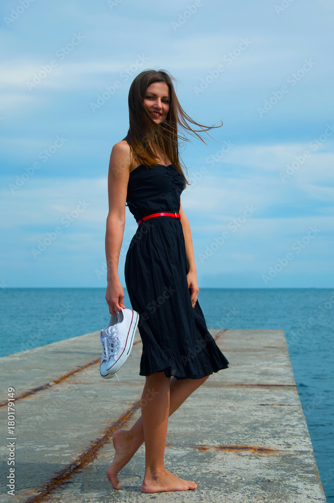 beautiful slender young woman in a black dress and barefoot on the pier Stock Photo | Adobe Stock beautiful slender young woman in a black dress and barefoot on the pier Stock Photo | Adobe Stock