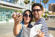 © innervisionpro - Happy couple in sunglasses holding map laughing