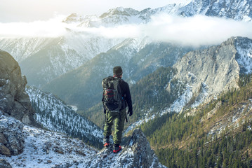 man hiker with backpack on top of the mountain back, looking at the snow slope. concept motivation a