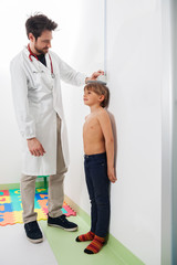 A pediatric doctor controlling the growth of the blond hair boy